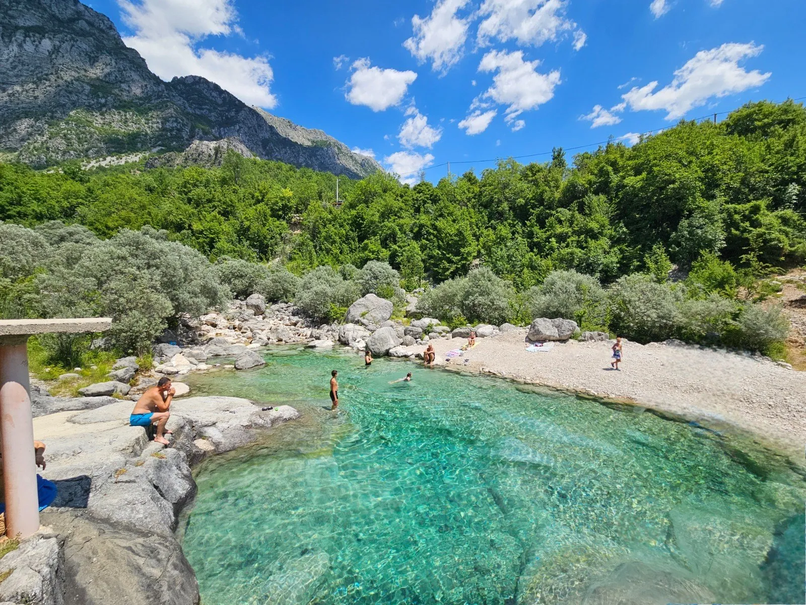 Swimmers in a clear turquoise river pool below limestone mountains in Herzegovina